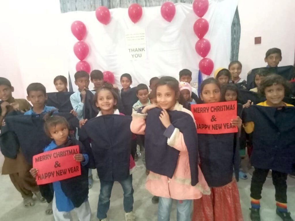 Students of St. Peter's show signs with "Merry Christmas & Happy New Year" and the warm sweaters they received as a gift