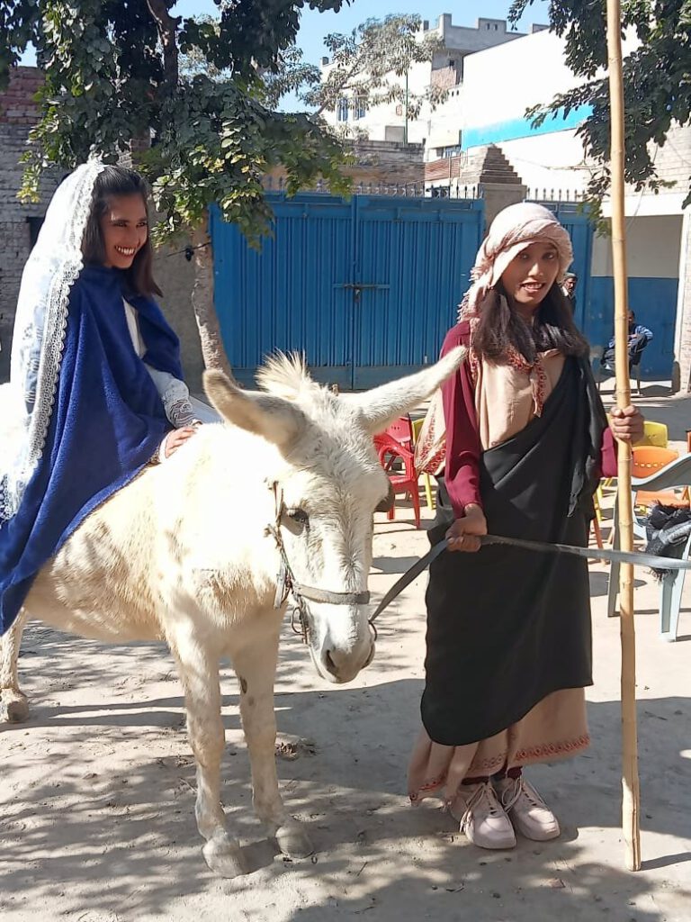 Christmas play: Joseph and Mary (riding on a real white donkey) are searching for a shelter