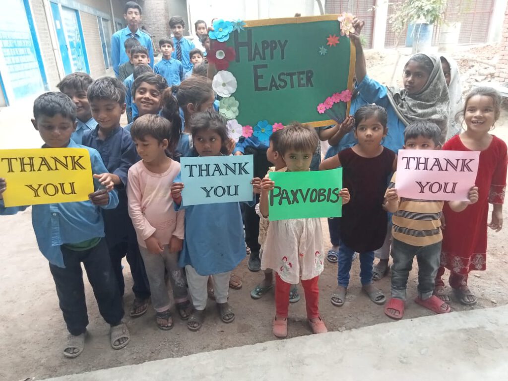Group of students lifting up posters with the words "Happy Easter", "Thank you", and "Paxvobis".