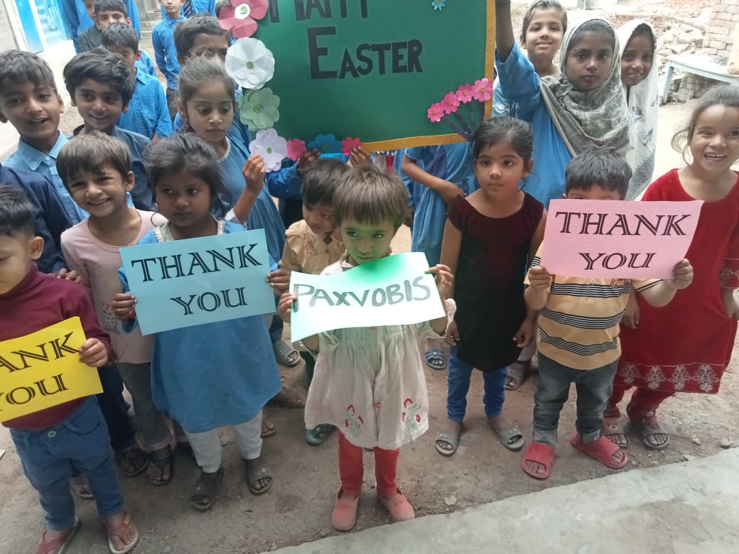 Group of students lifting up posters with the words "Happy Easter", "Thank you", and "Paxvobis".